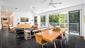 A spacious kitchen with a dining area, large windows, and a view of the outdoors. - Unique Home in Dauphin Island's Maritime Forest - Stunning Home and Water Views (Dauphin Island)
