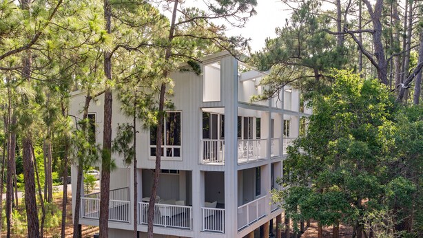 A multi-story cabin with balconies, surrounded by trees. - Unique Home in Dauphin Island's Maritime Forest - Stunning Home and Water Views (Dauphin Island)