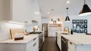 Una cocina moderna con armarios blancos, electrodomésticos de acero inoxidable y encimera de mármol.