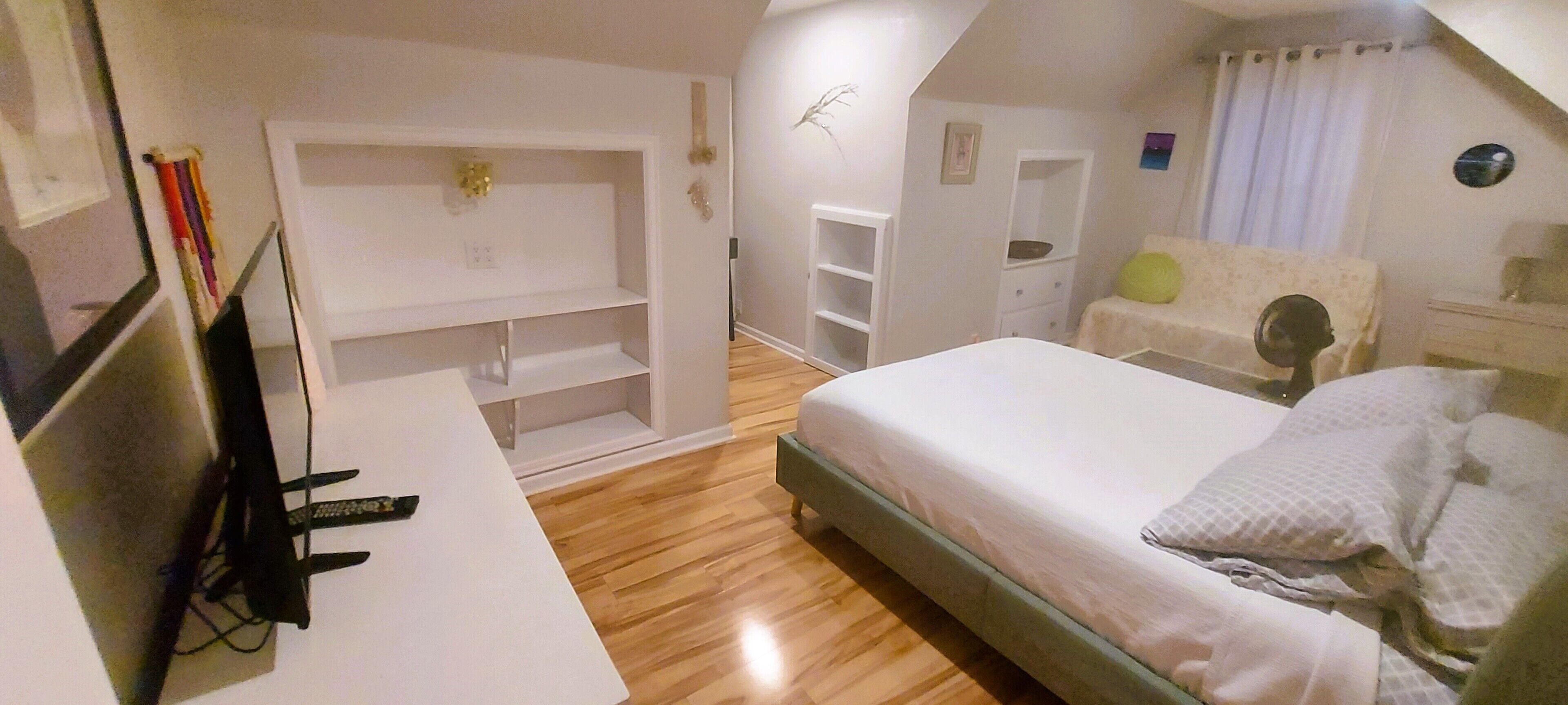 A bedroom with a bed, a desk, and a TV.