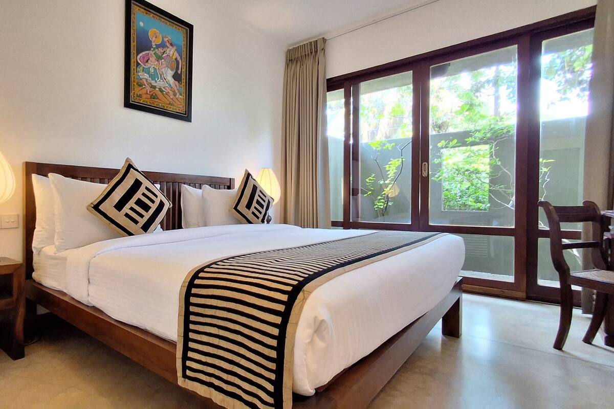 A neatly made bed with a striped blanket, a bedside lamp, and a framed picture on the wall.
