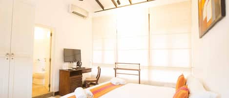 A bedroom with a bed, a desk, a chair, a television, and a wardrobe.