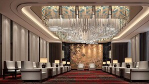 A spacious lobby with a long reception desk, modern chairs, and a decorative ceiling. - Wanda Realm Qiqihar (Qiqihar)