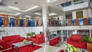 Una hall moderna con divani rossi, un tavolino in vetro e un'imponente colonna.