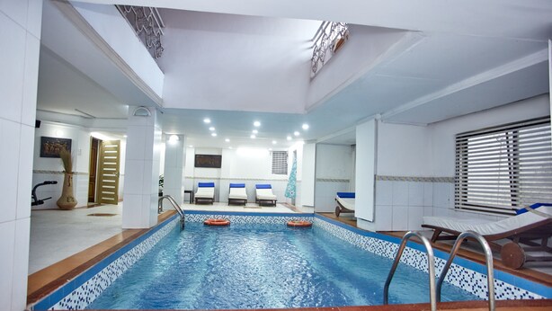Una piscina interna con bordo piastrellato, uno spogliatoio con doccia e un'area relax con lettini.
