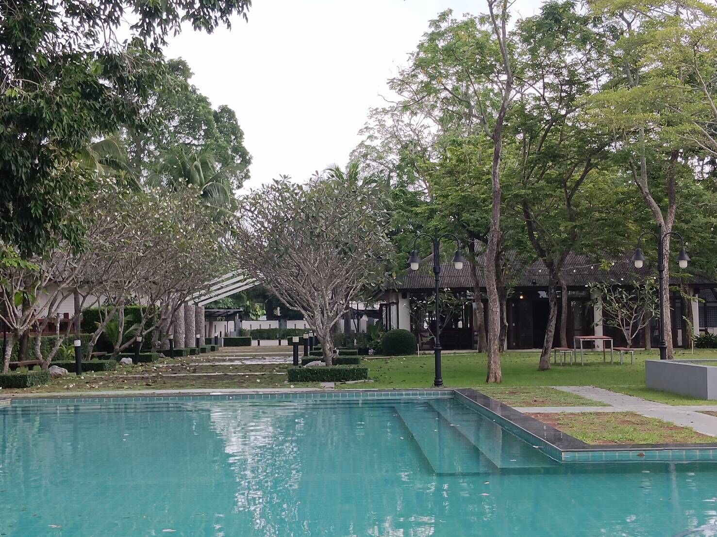 Una piscina rodeada de árboles y un edificio tradicional con techo de tejas.