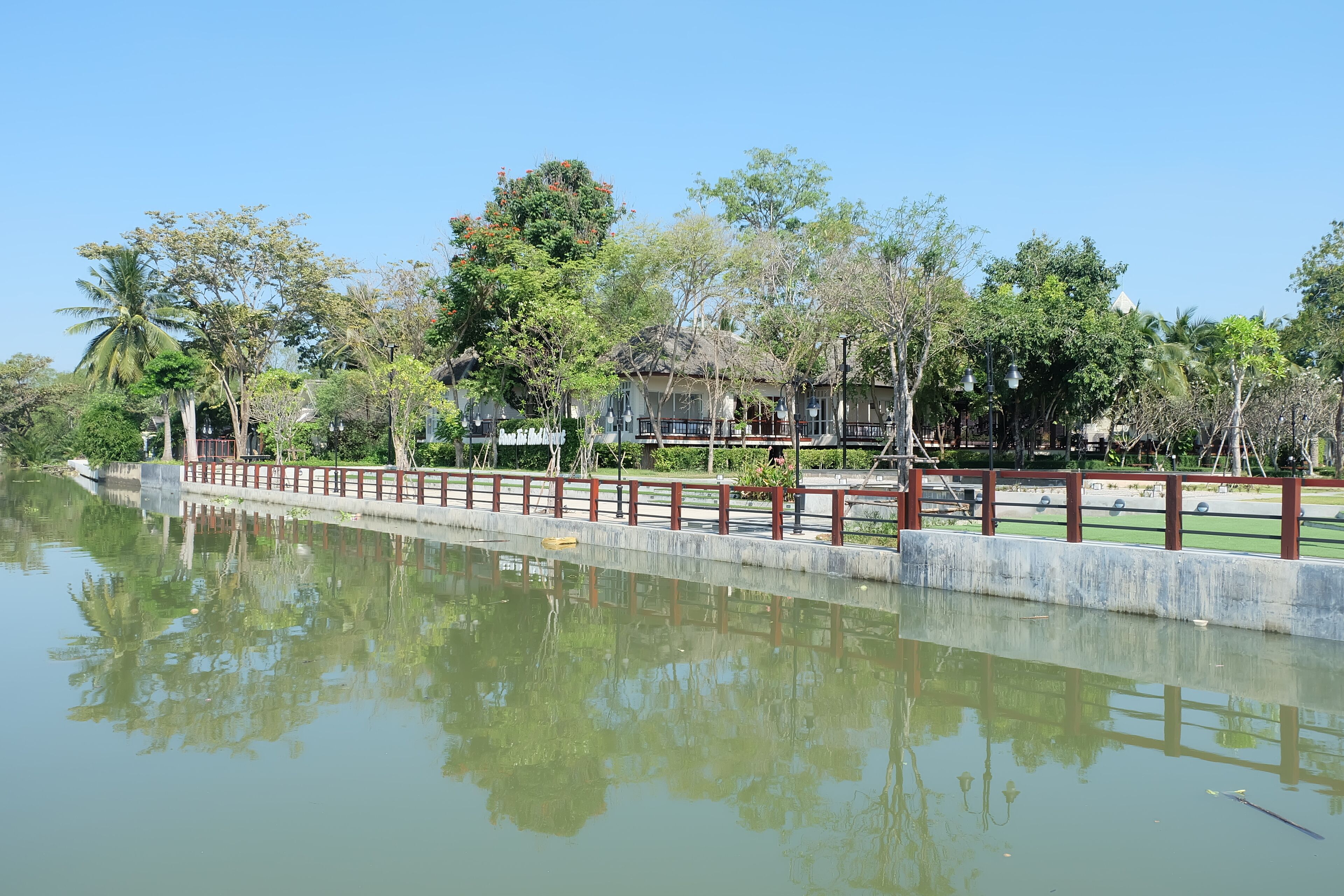 A calm water body with a wooden fence and trees in the background.