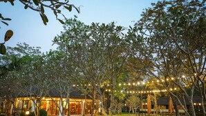 A well-lit outdoor area with string lights, benches, and a building with large windows. - Baan Tai Had Resort (Samut Songkhram)
