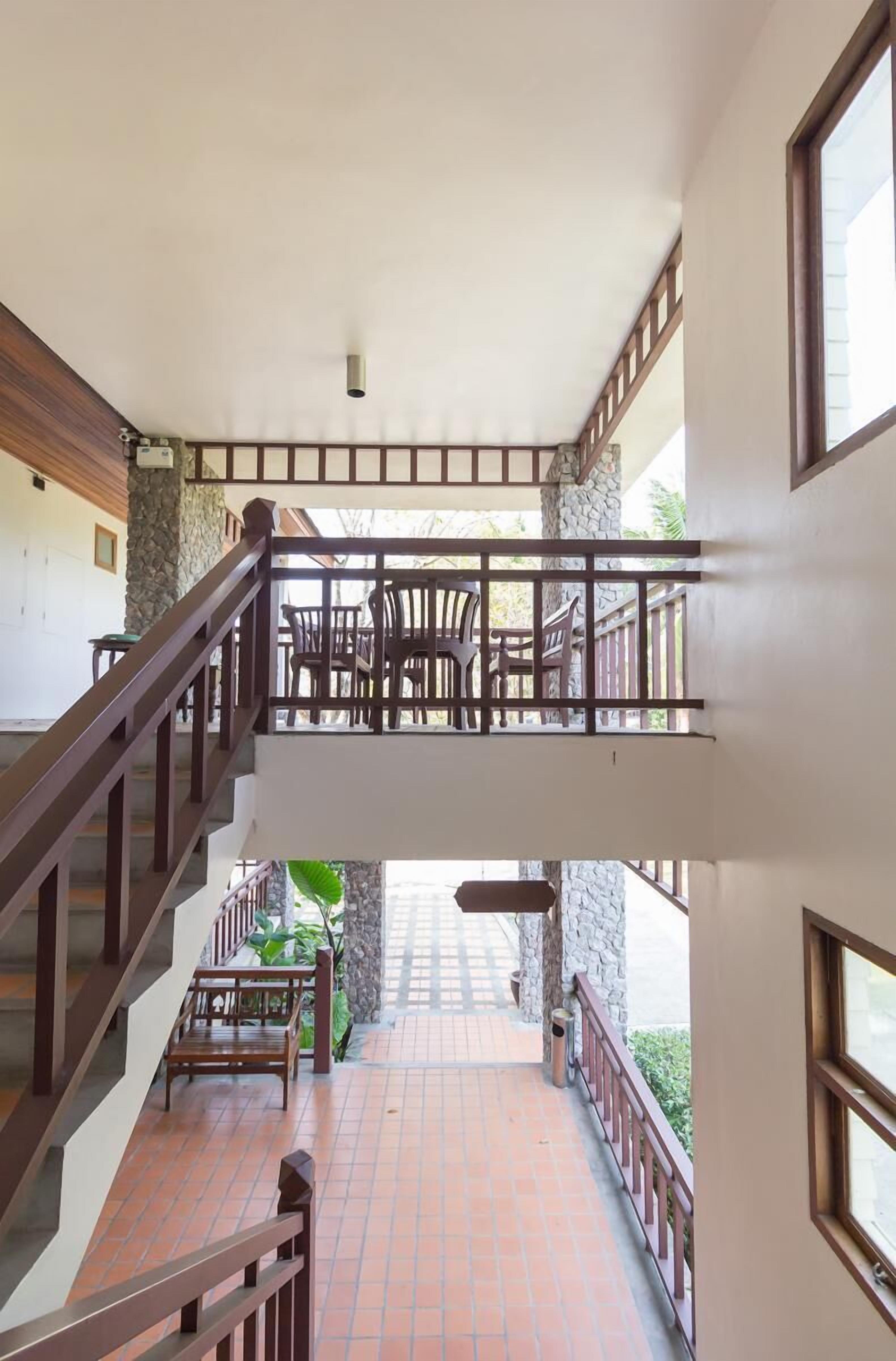 A multi-level interior with a staircase, a balcony with outdoor seating, and a stone wall.
