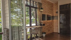 A modern kitchen with wooden accents, a dining area with a table and chairs, and a large window with curtains. - Baan Tai Had Resort (Samut Songkhram)