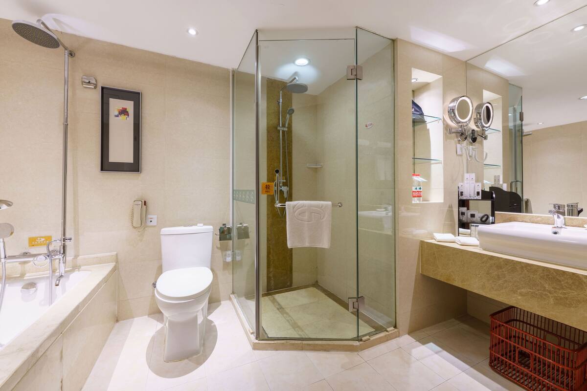 A modern bathroom with a glass-enclosed shower, a toilet, a bathtub, and a vanity with a mirror.
