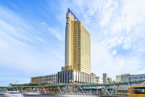 A tall hotel with a modern design, featuring a prominent sign and a covered walkway in front.