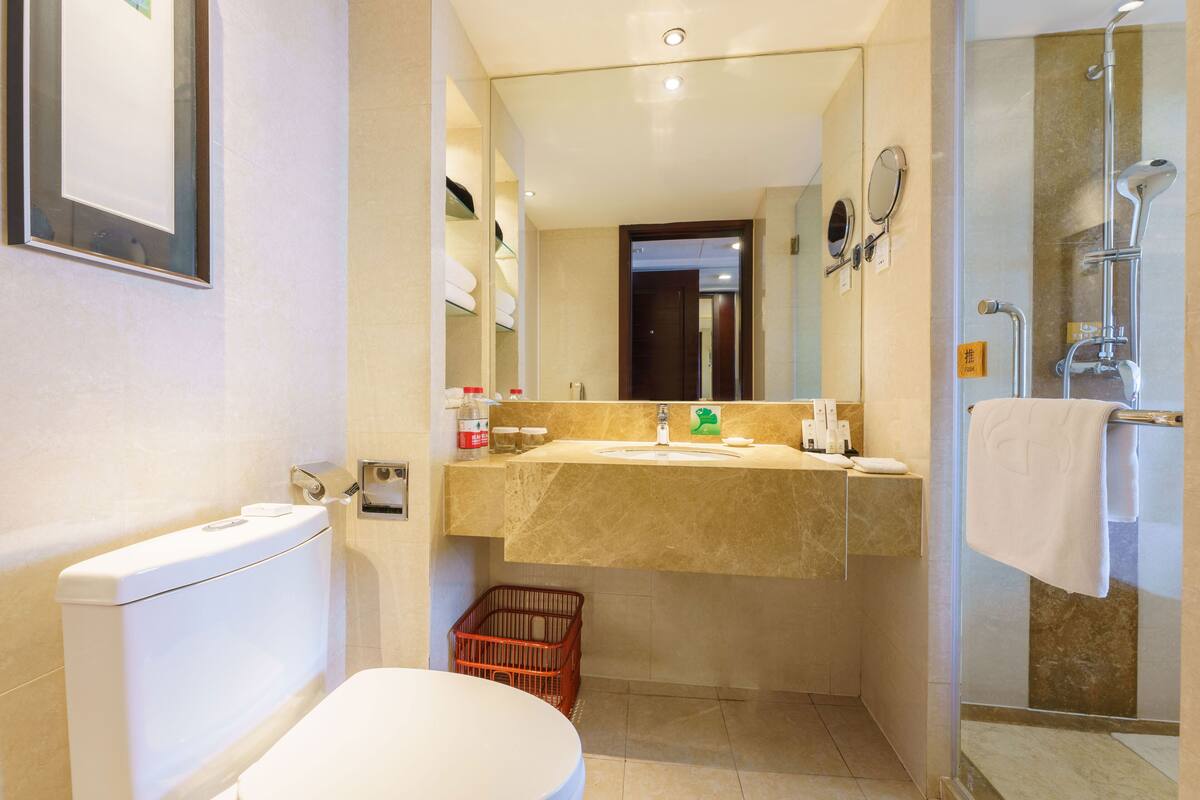 A bathroom with a toilet, sink, and shower.