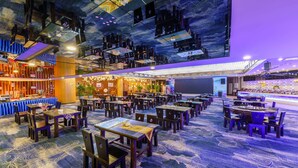 A spacious restaurant with multiple tables and chairs, a bar area, and a ceiling mural. - Oasis Grand Hotel (Ürümqi)
