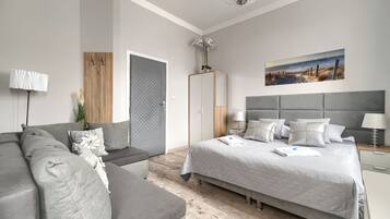 Un dormitorio moderno con una cama grande, un sofá, un armario y un cuadro en la pared.