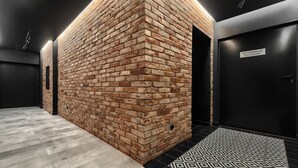 A modern interior with exposed brick walls, a black door labeled "RESTAURACJA RESTAURANT," and a patterned floor. - Stawa Villa & Apart (Swinoujscie)