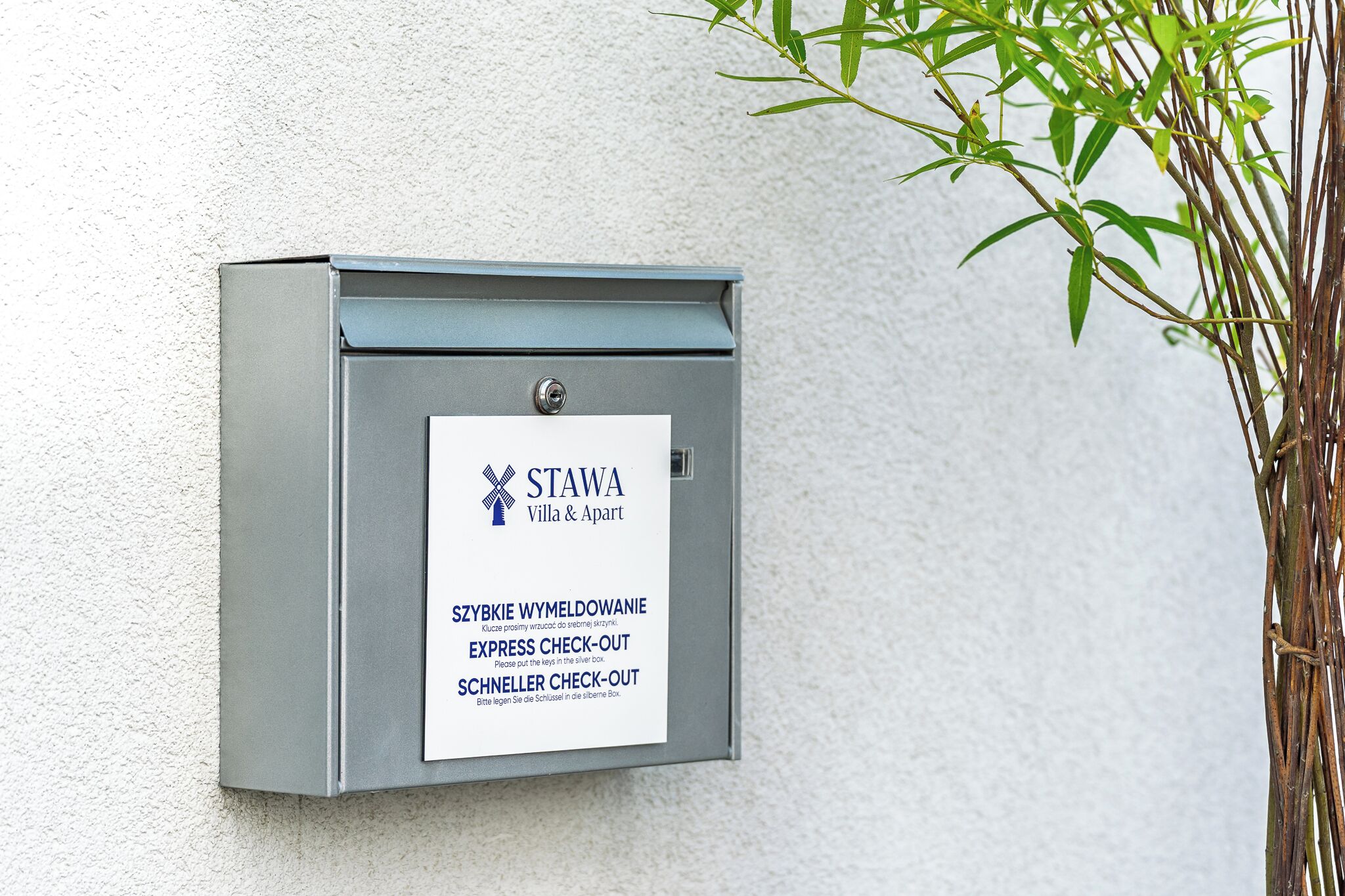 En metallåda för diverse förnödenheter med en vit etikett för Stawa Villa & Apart, som innehåller instruktioner för snabb utcheckning (express- och Schnelller-utcheckning).