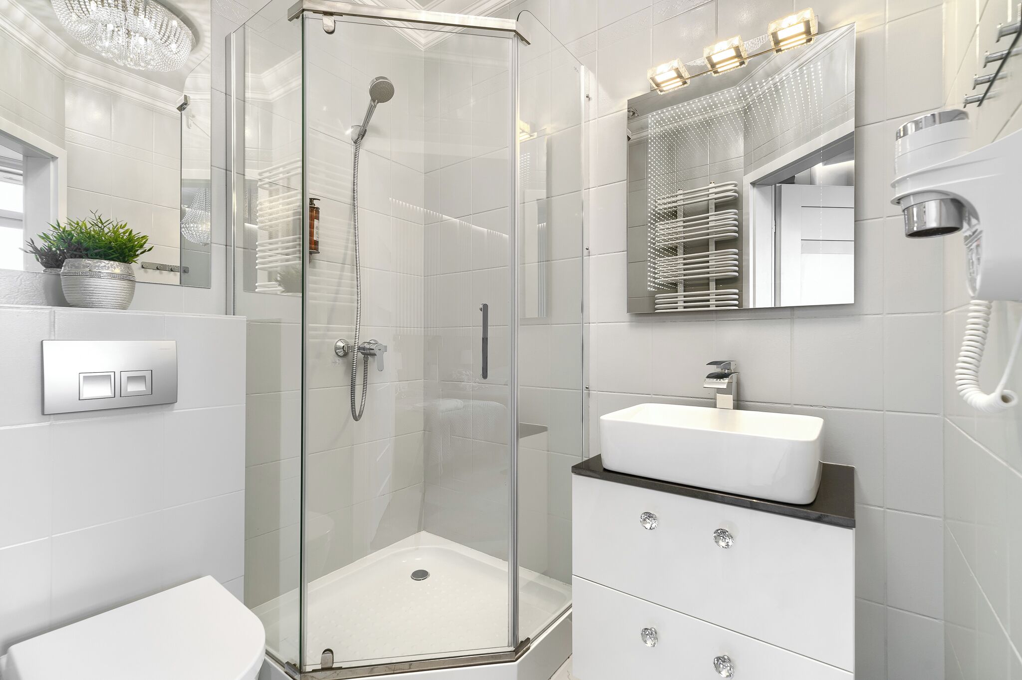 Un baño moderno con ducha acristalada, lavamanos blanco y tocador con cajones.