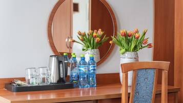 Ein Holztisch mit einem Spiegel, zwei Vasen mit Tulpen, einer Kaffeemaschine und Wasserflaschen.