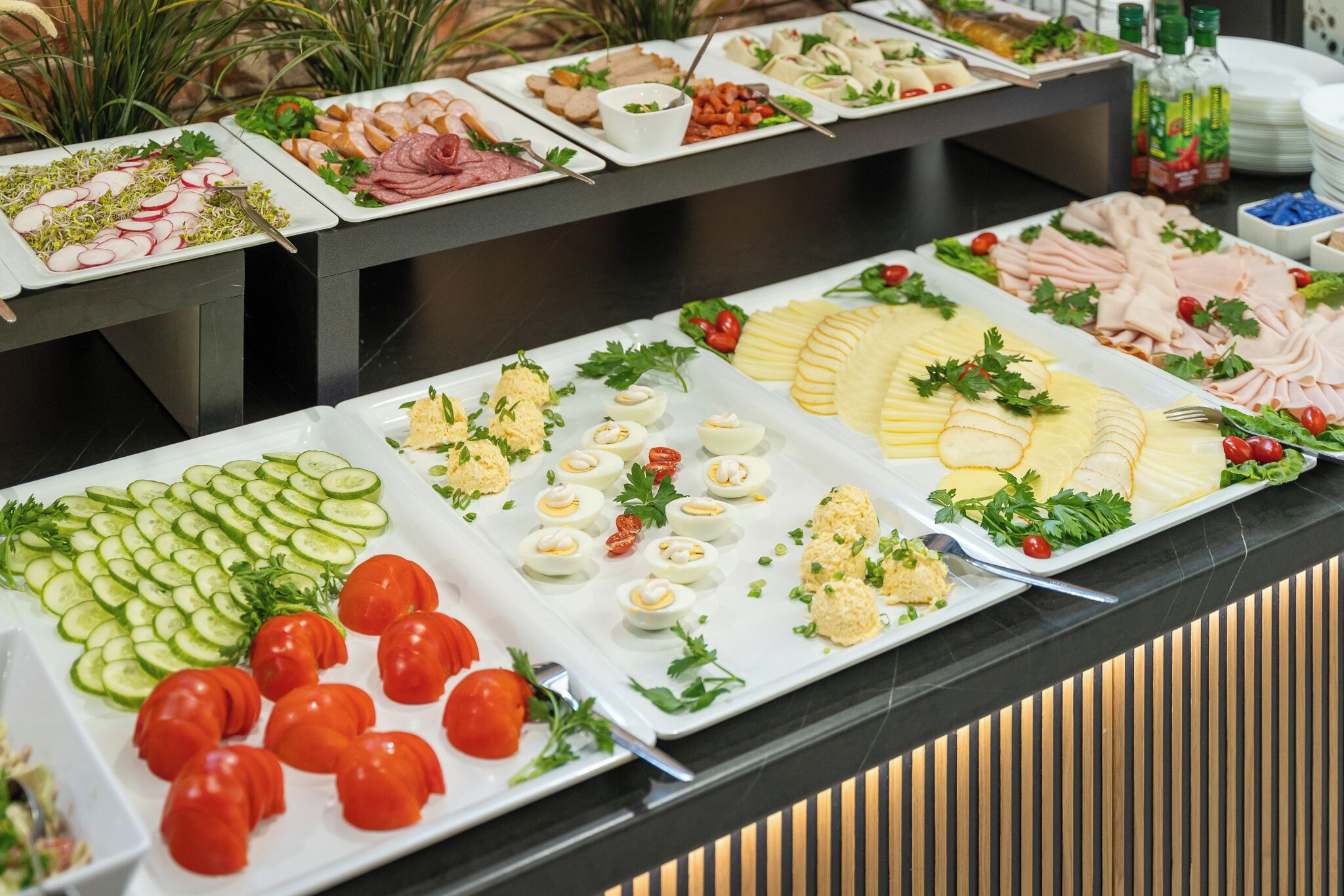 A buffet with various food items including sliced meats, cheeses, and vegetables.