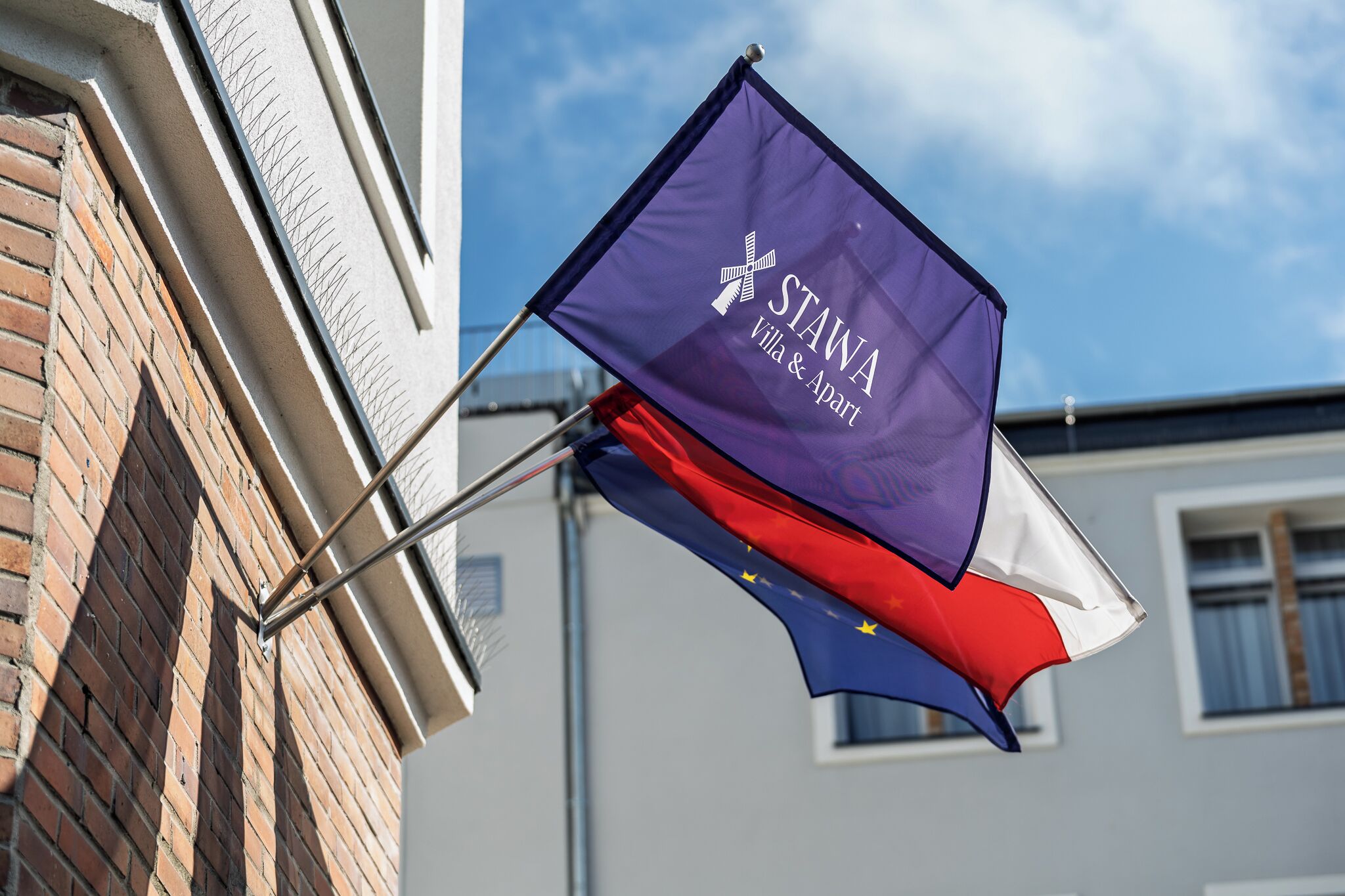 Eine Flagge mit dem Text 'STAWA Villa & Apart' und einem Kreuz-Symbol.