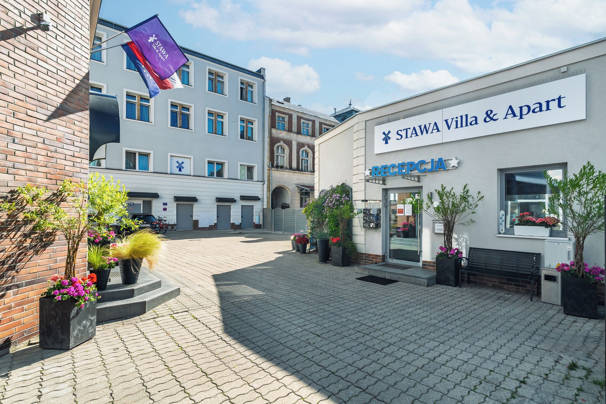 Une cour avec un bâtiment portant l’inscription « STAWA Villa & Apart » et un drapeau.
