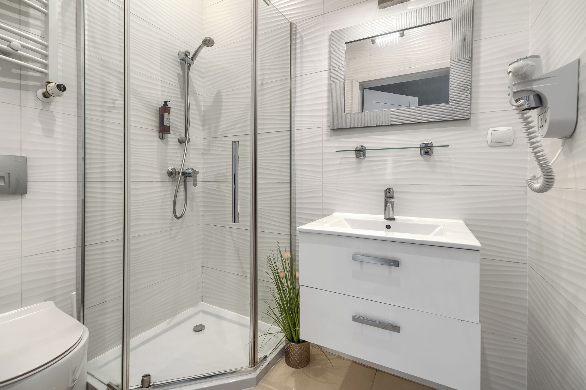 A modern bathroom with a glass-enclosed shower, a white sink, and a mirror above the sink.