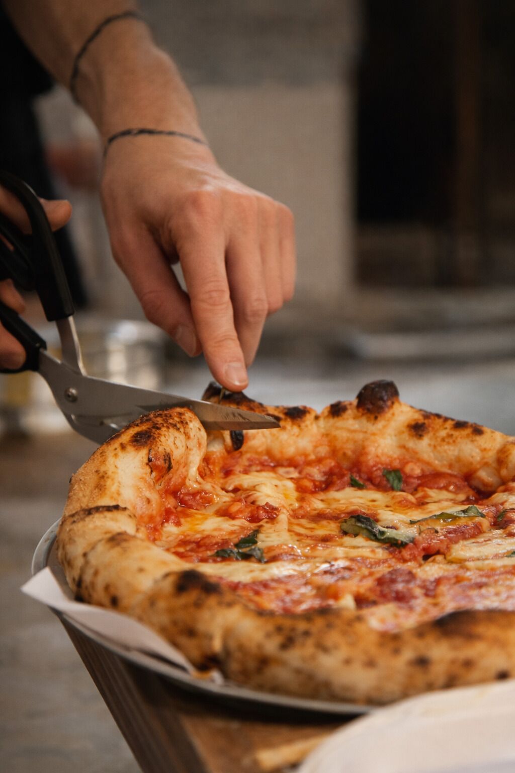 Una persona cortando una pizza con un cortador de pizza.
