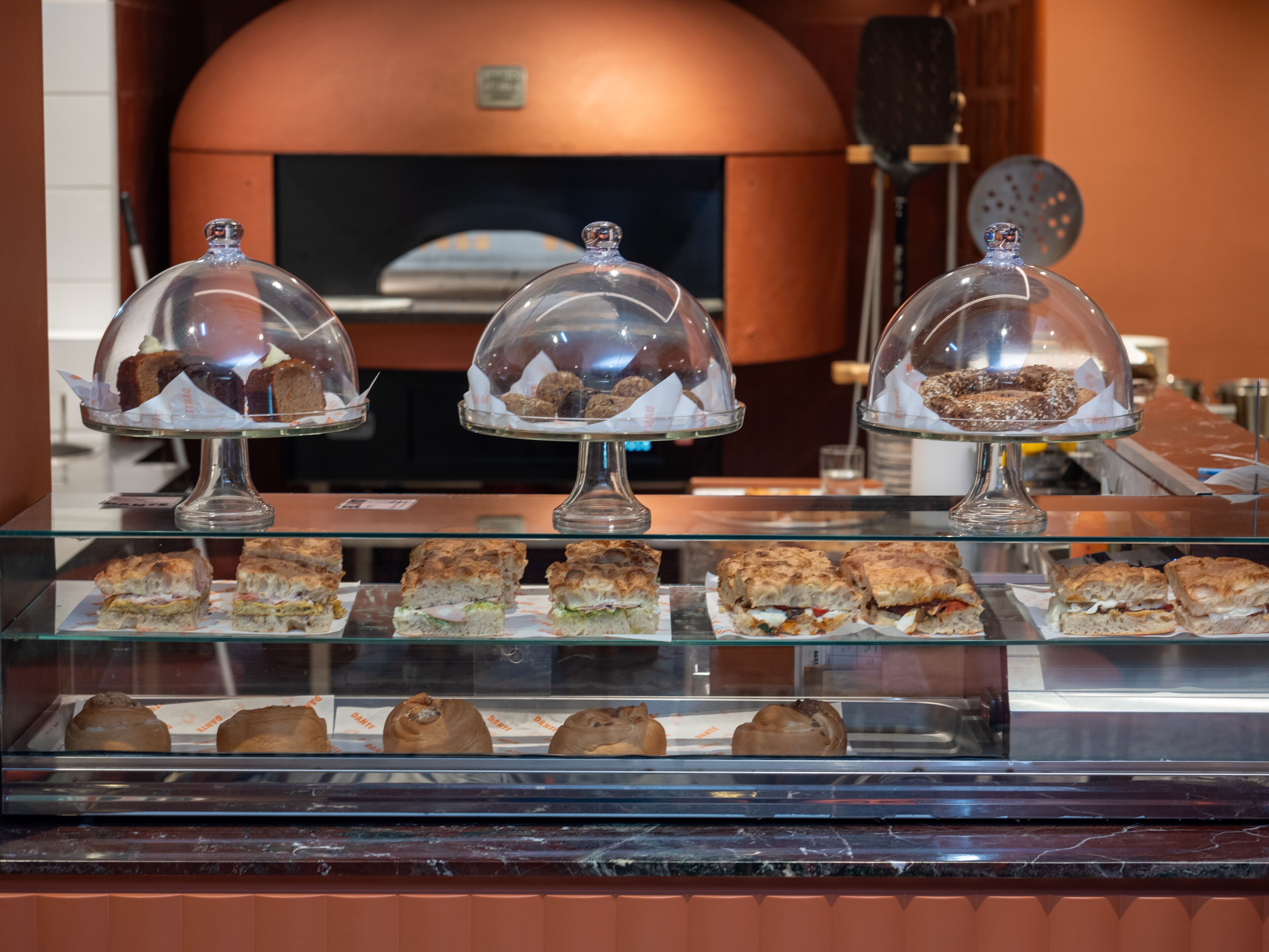 Une vitrine de boulangerie présentant diverses pâtisseries sous des cloches de verre.
