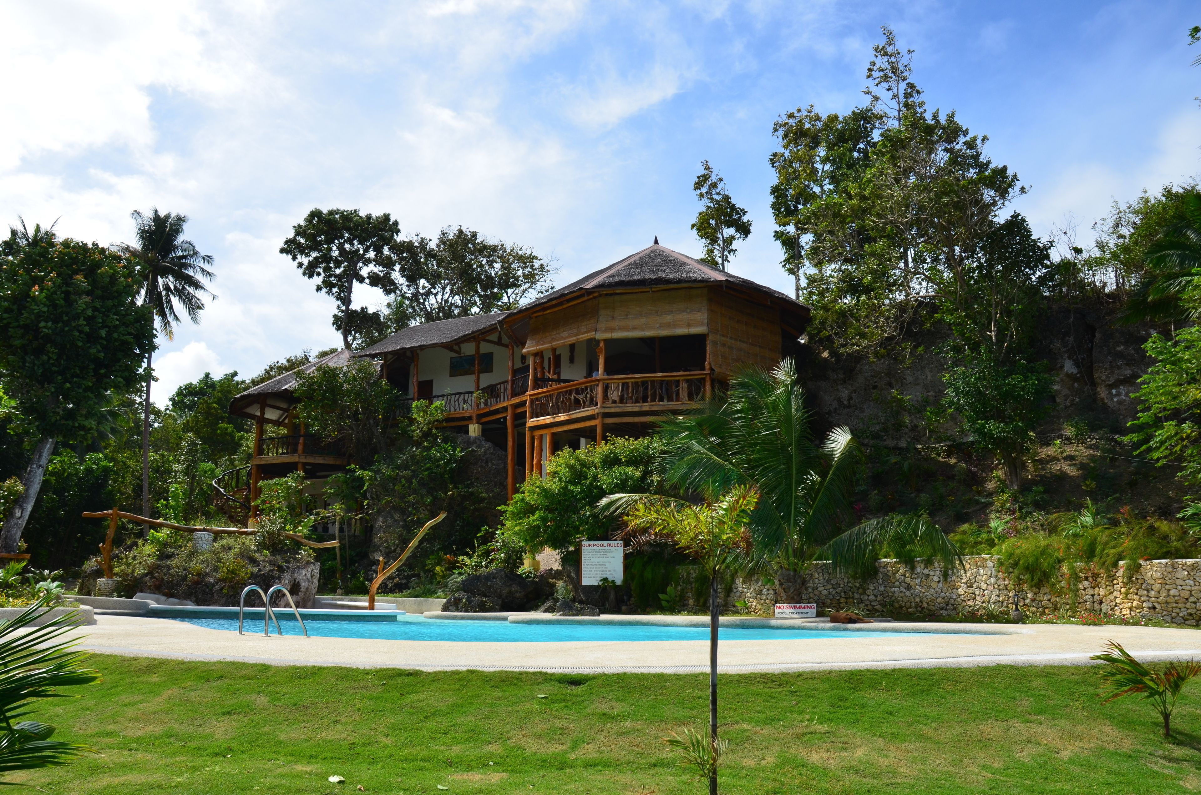 Une grande maison avec une piscine et une terrasse en bois.