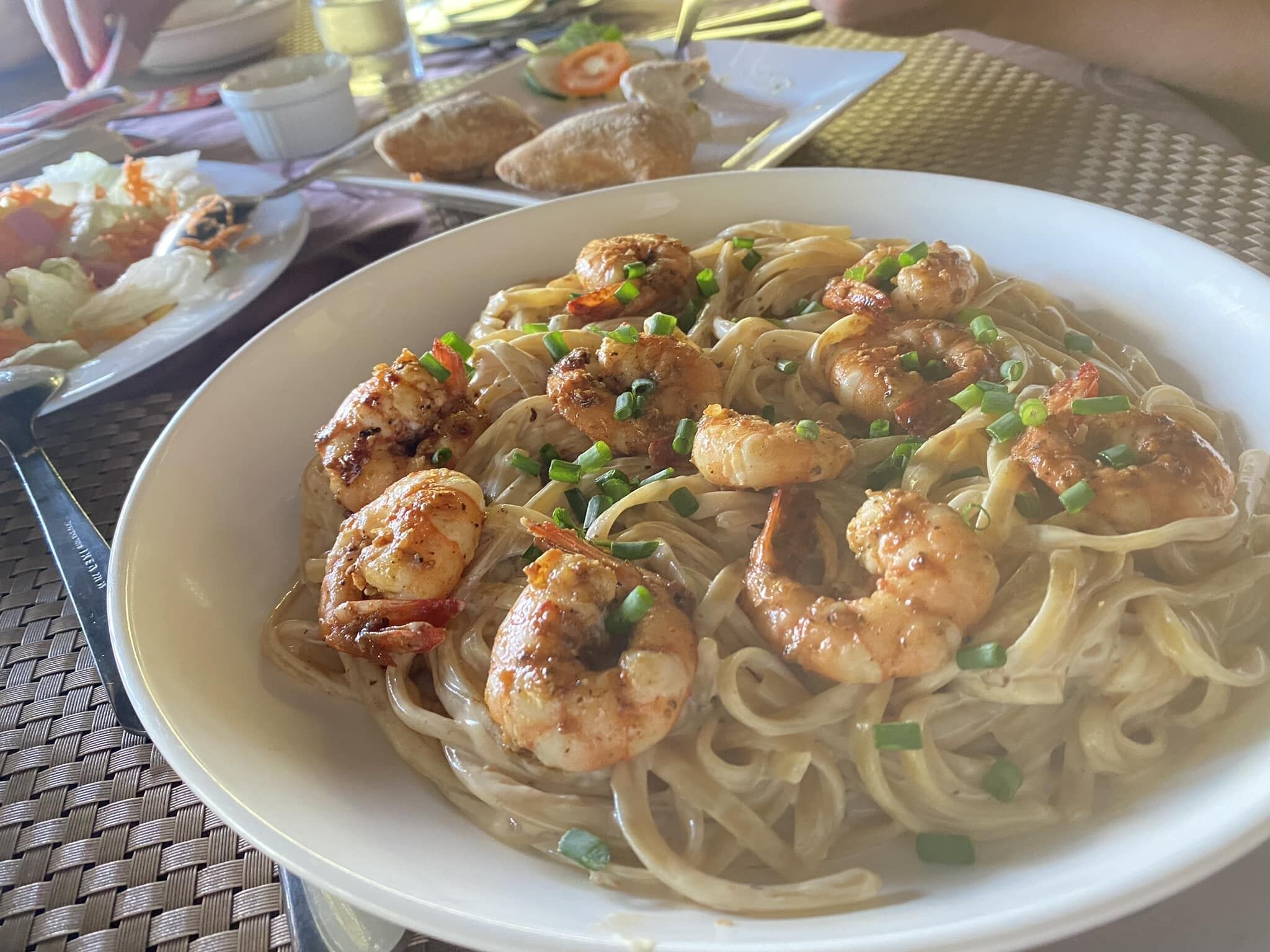 A bowl of noodles with shrimp and green onions.