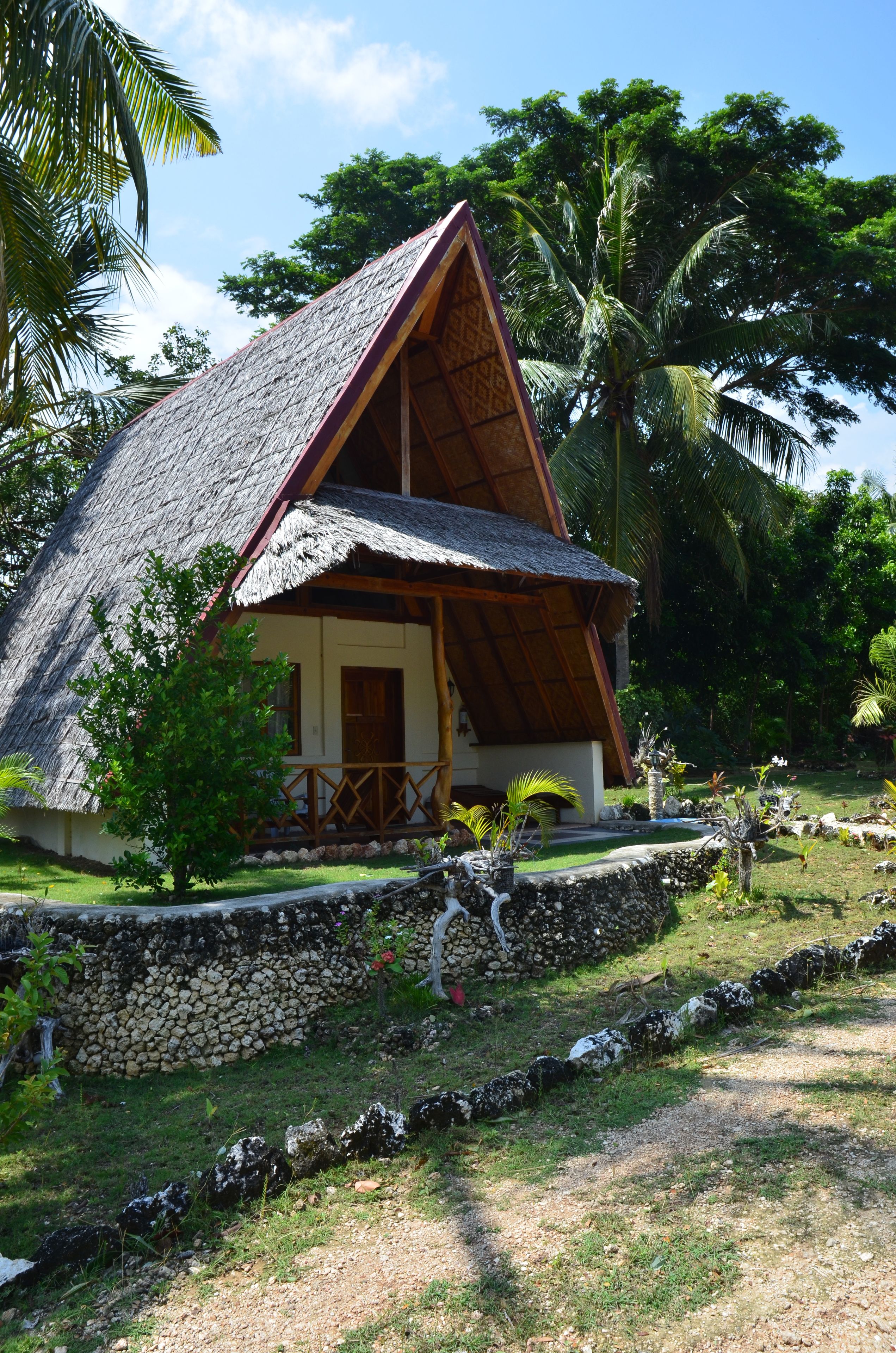 A thatched-roof house with a stone wall and a small garden.