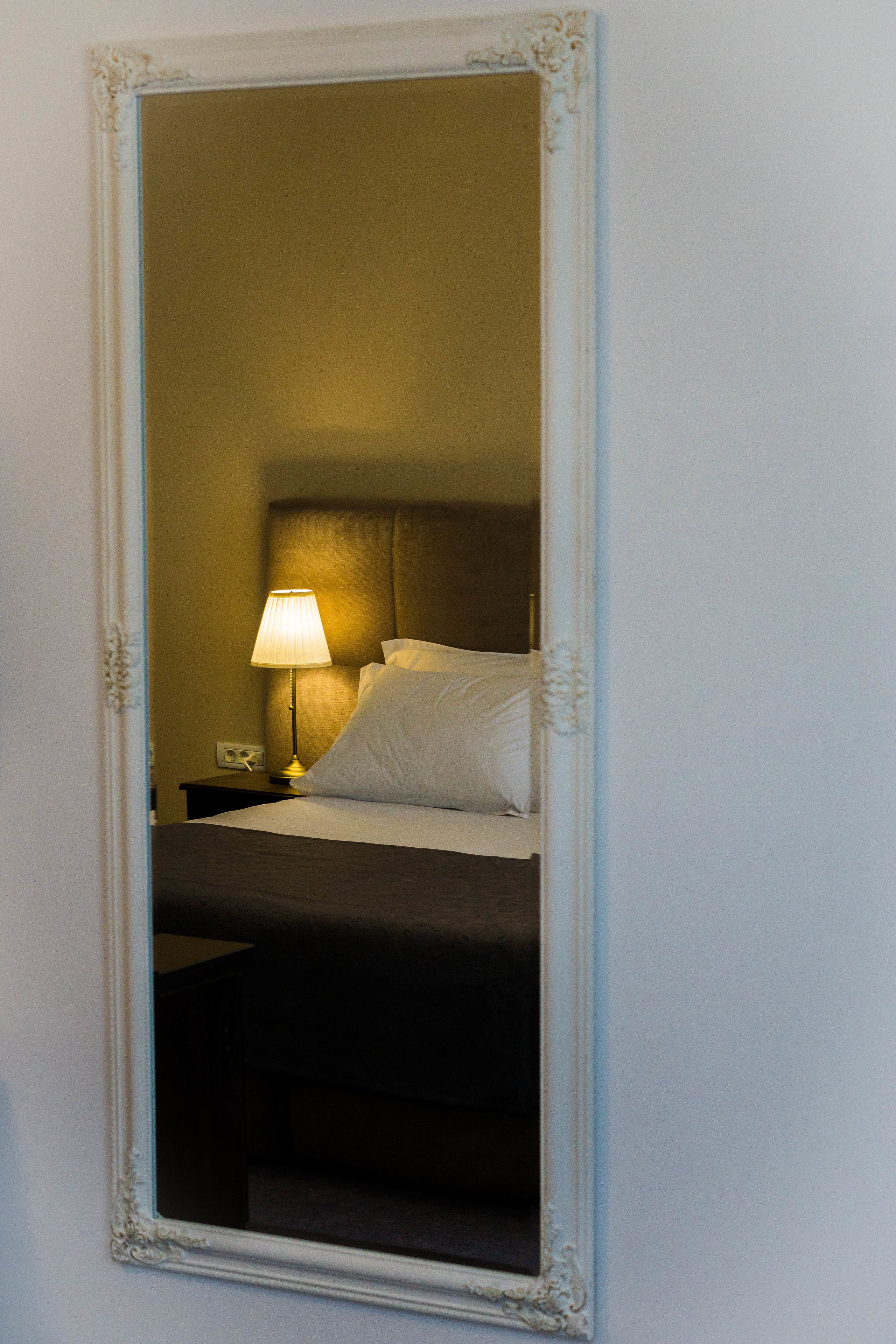 Une chambre d’hôtel avec un lit, une table de chevet, une lampe et un miroir.
