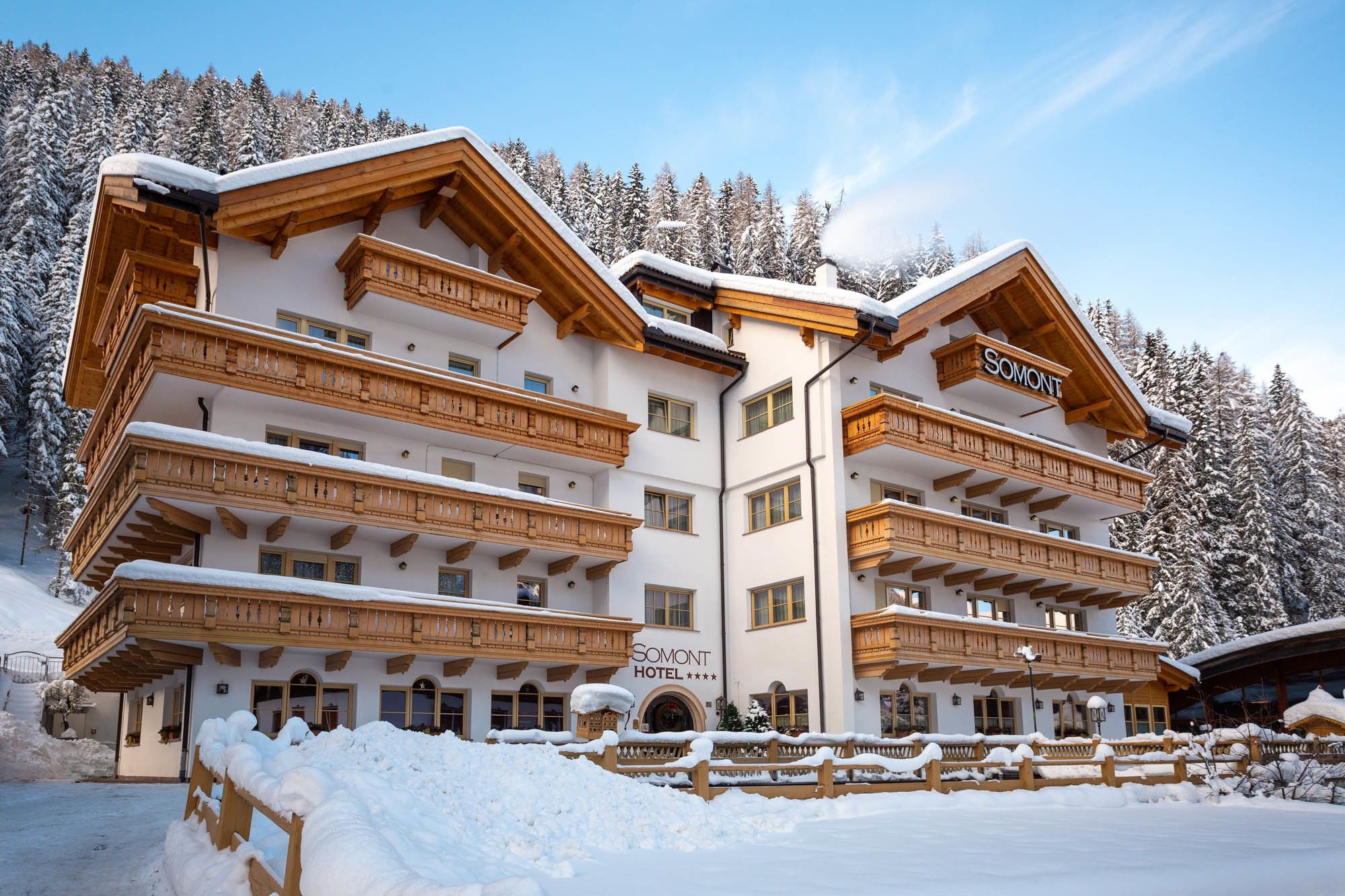 Ein großes, mehrstöckiges Hotel mit hölzernen Balkonen und verschneiter Landschaft.