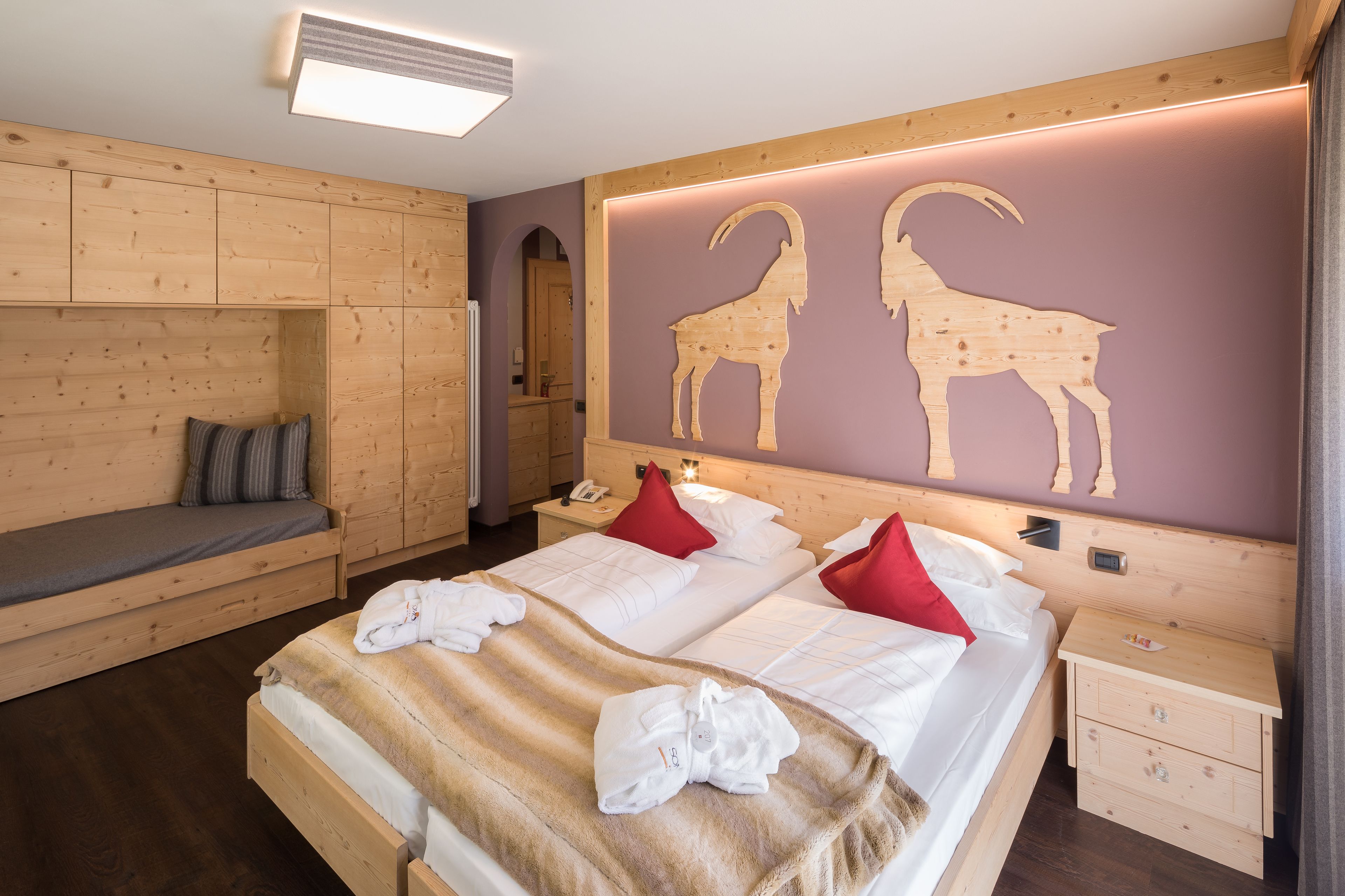 A wooden-themed bedroom with a bed, bedside tables, and a wooden bench.