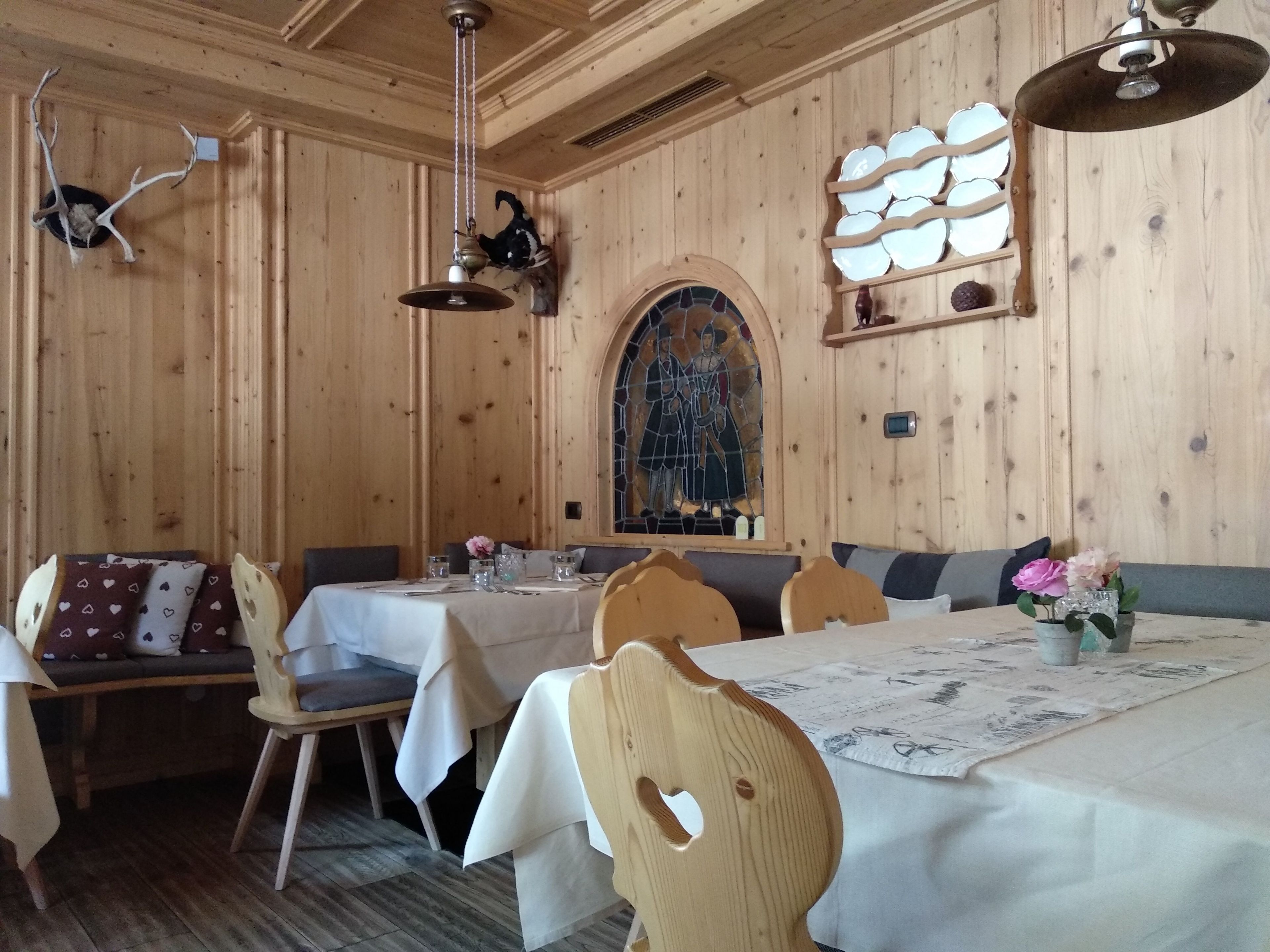 Un intérieur en bois comprenant un coin repas avec des tables et des chaises, un vitrail et des décorations murales.