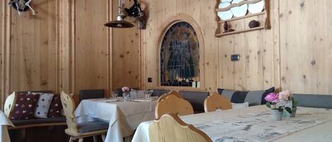 Un intérieur en bois comprenant un coin repas avec des tables et des chaises, un vitrail et des décorations murales.