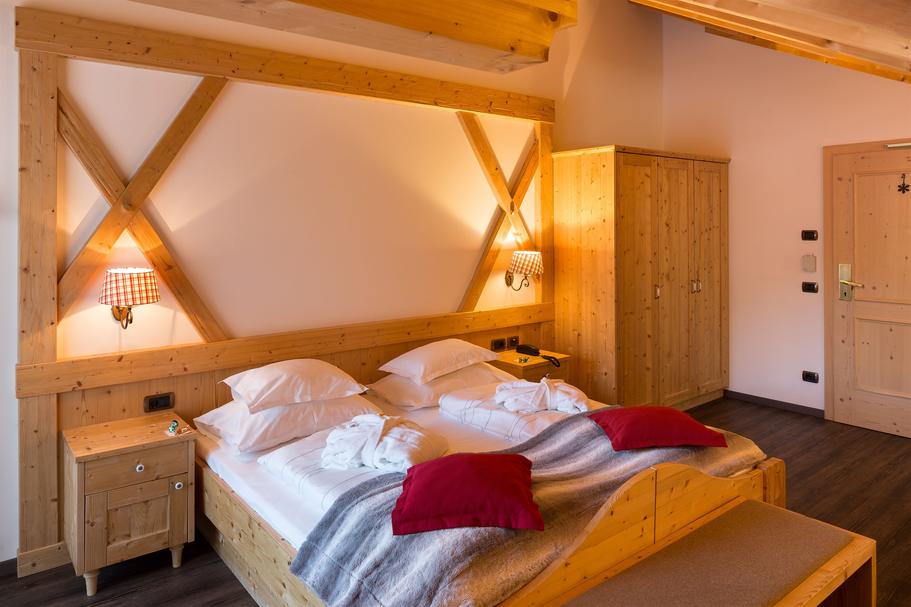 Un dormitorio de madera con cama, mesitas de noche y un armario.