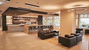 A spacious modern kitchen with a central island, bar seating, and a seating area with sofas and chairs. - Seehotel Maria Laach (Glees)
