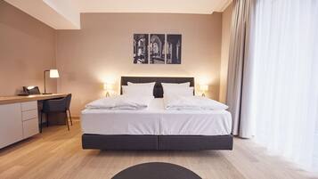 A modern hotel room with a large bed, a desk, and a chair.