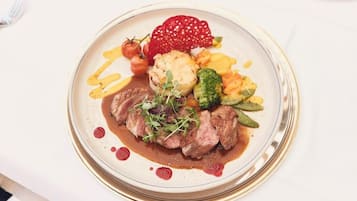 A plate of food with steak, vegetables, and a red fruit garnish.