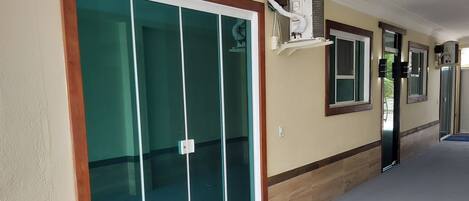 A hallway with a sliding glass door, a window with a view, and a wall-mounted air conditioning unit.
