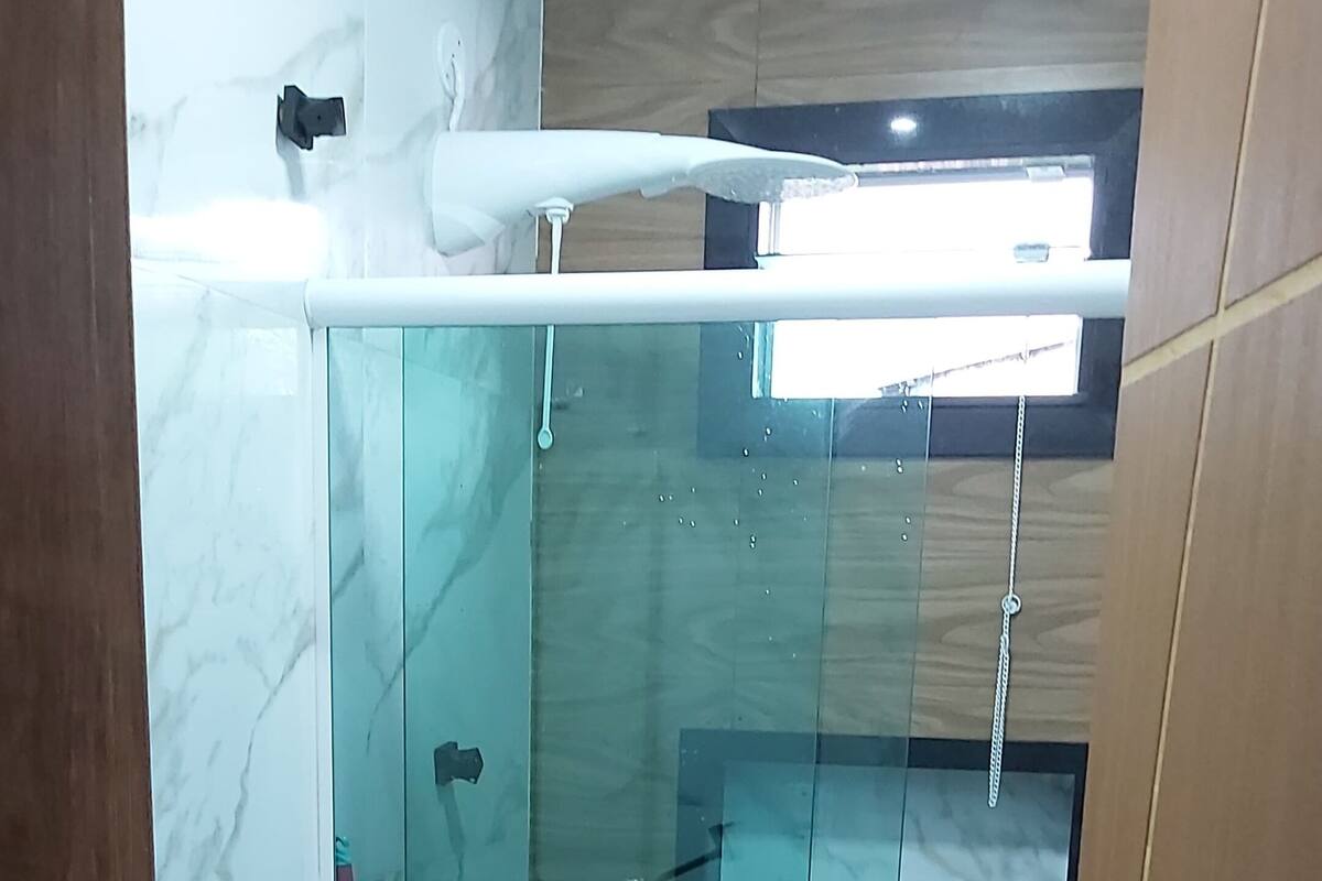 Moderni kylpyhuone, jossa on lasiseinällä varustettu suihku, wc ja pesuallas.