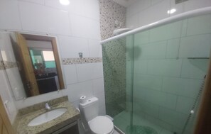 Un baño con lavamanos, inodoro y cabina de ducha de vidrio.