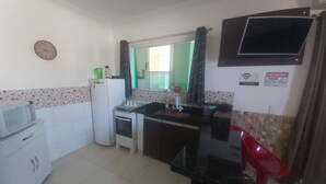 A compact kitchen with a microwave, stove, sink, and a small refrigerator. - Praia do Foguete Style (Cabo Frio)