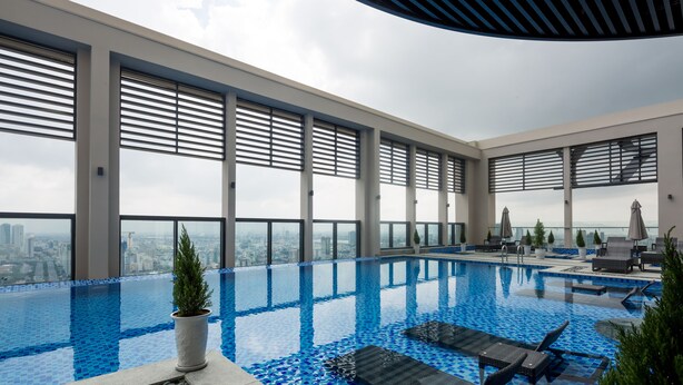 Une piscine intérieure moderne, avec des carreaux bleus transparents, des chaises longues et des plantes en pot.
