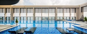 A modern indoor swimming pool with clear views of the cityscape through large windows. - Luxury Apartment Ocean View (Da Nang)