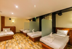 Habitación de hotel con piso a cuadros, una cama y mesita de noche de madera, además de un espejo.