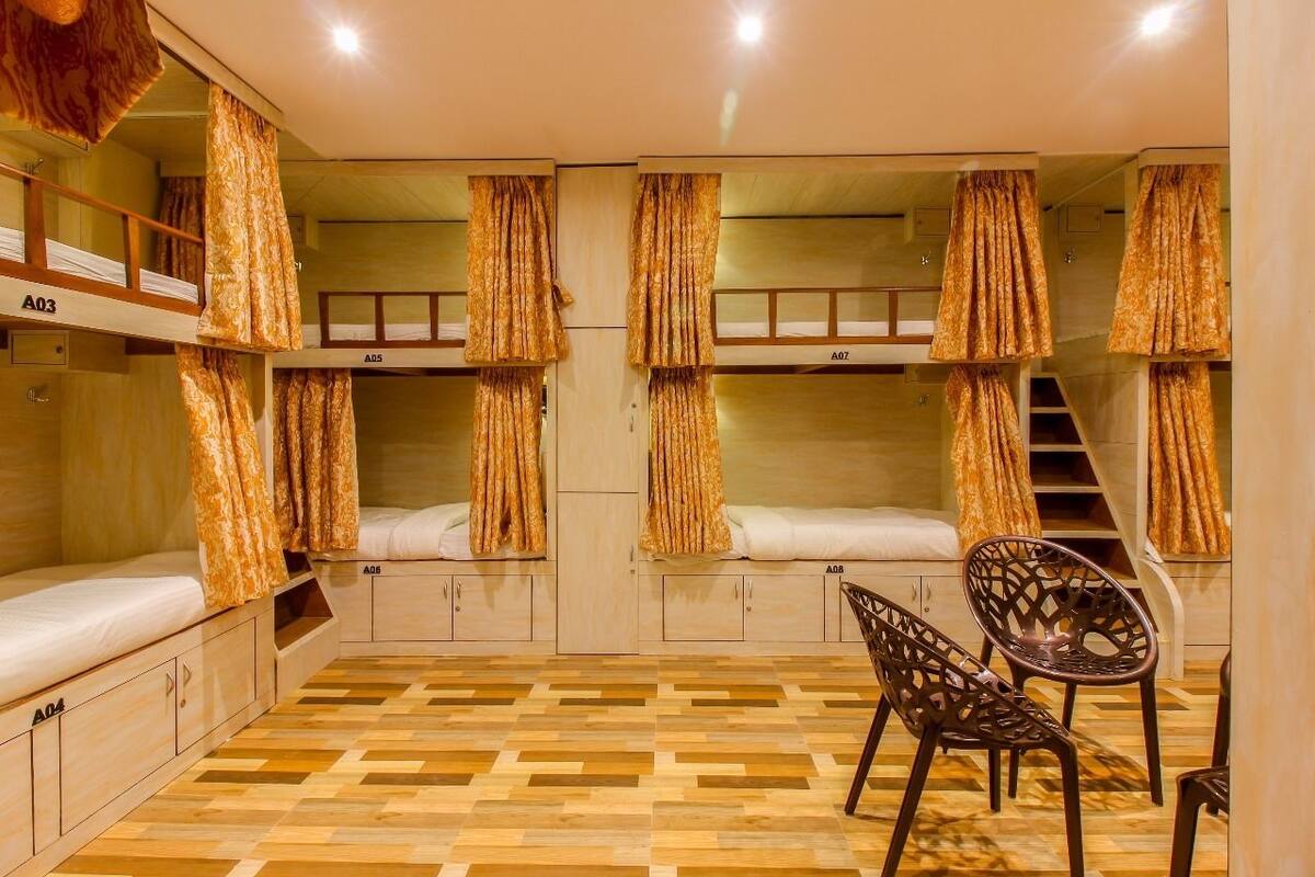 Un dormitorio con literas, piso de madera y una silla.