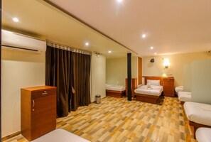Habitación de hotel con mostrador de recepción, armario de madera, cama con cabecera de madera, mesita de noche y aire acondicionado de pared.